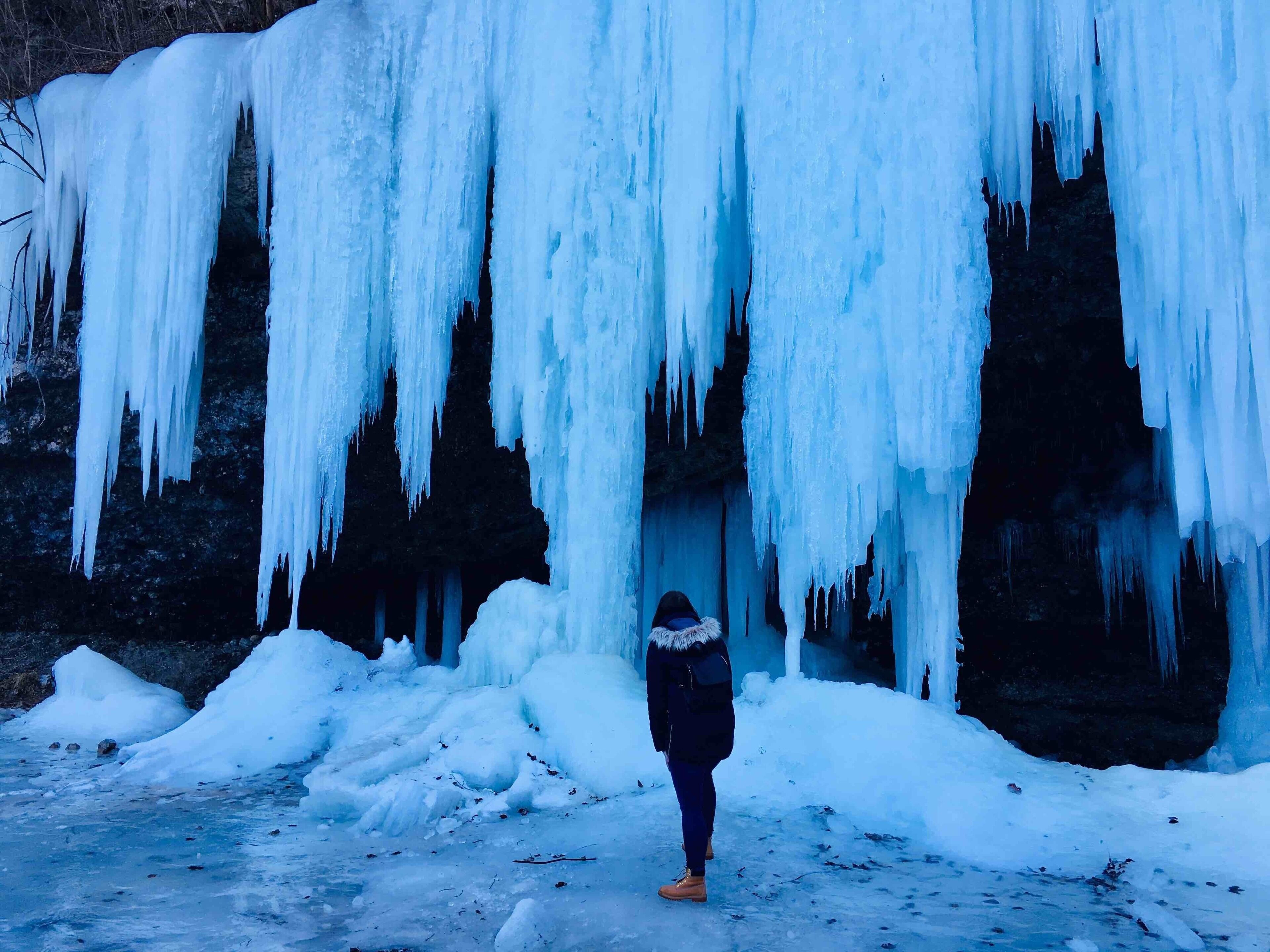A person standing in front of a large ice formation.