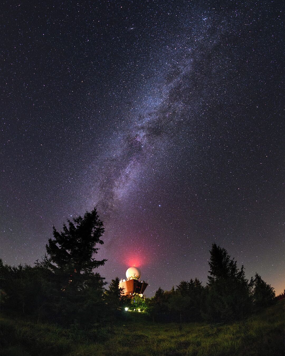 A night sky filled with stars and the Milky Way, with a dome-shaped observatory in the foreground.