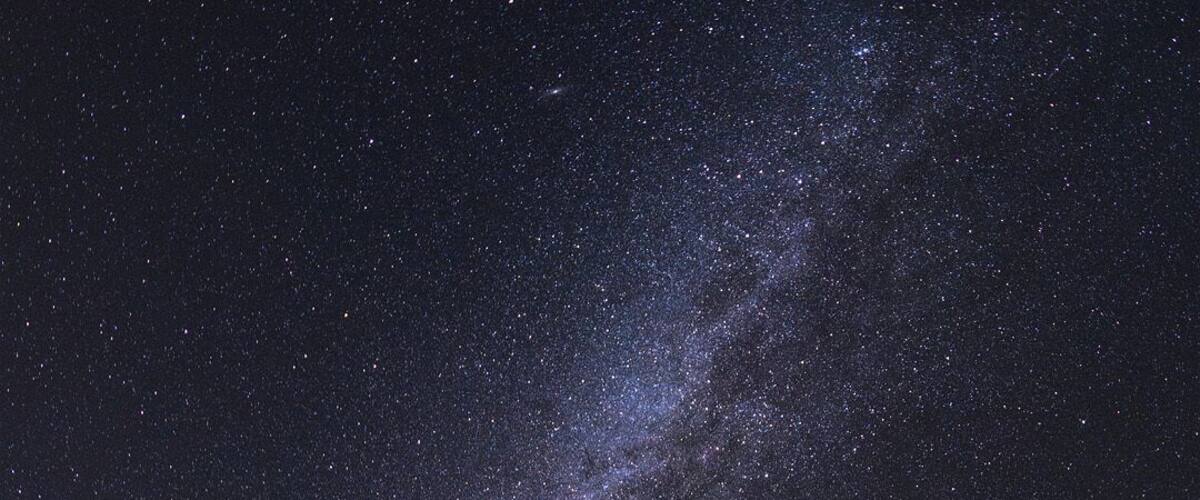 A night sky filled with stars and the Milky Way, with a dome-shaped observatory in the foreground.