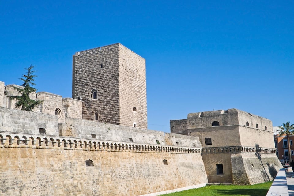 A historic stone fortress with a prominent square tower and a fortified wall with crenellations.