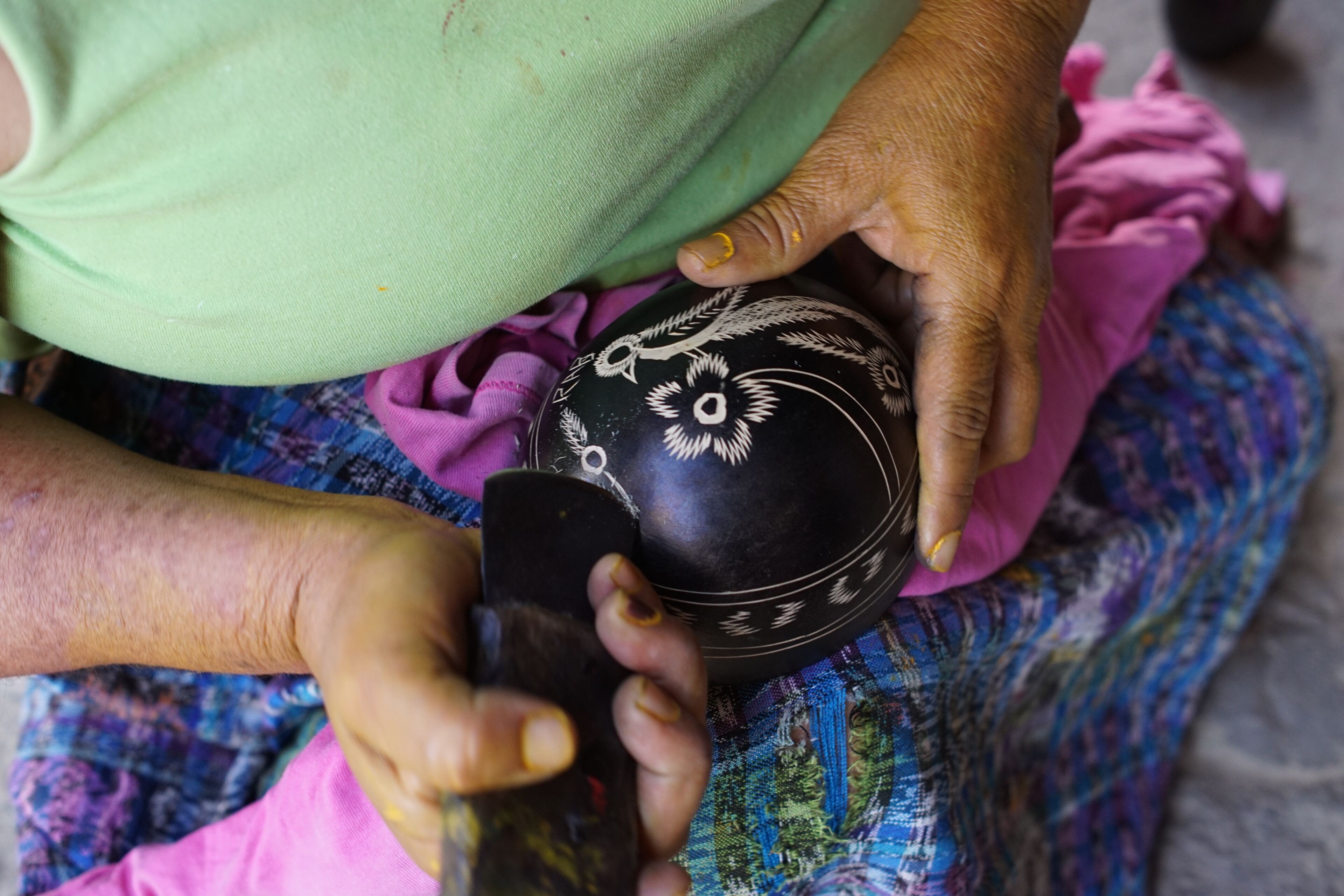 A person holding a black bowl with white designs.
