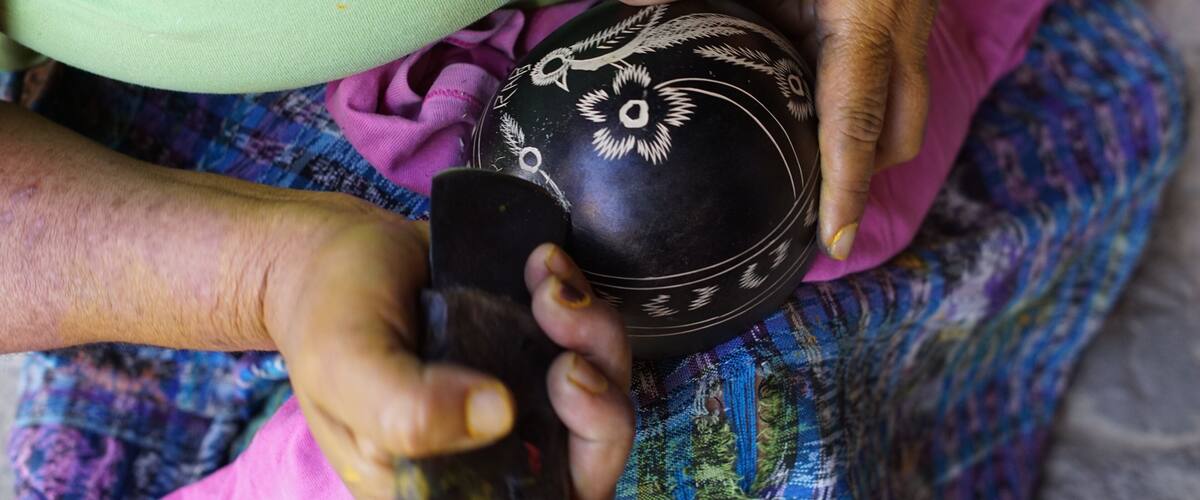 A person holding a black bowl with white designs.
