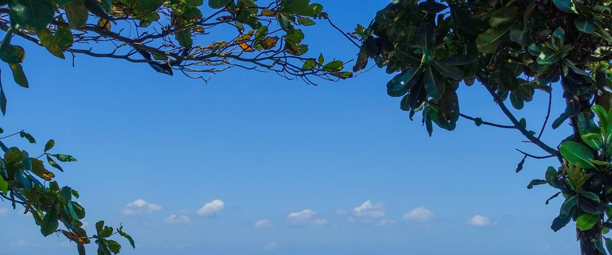 A beach with waves crashing against rocks and a clear blue sky.