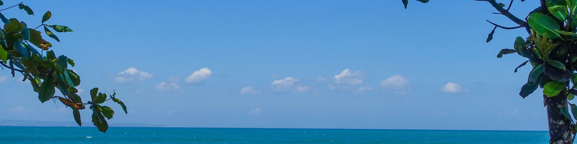 A beach with waves crashing against rocks and a clear blue sky.