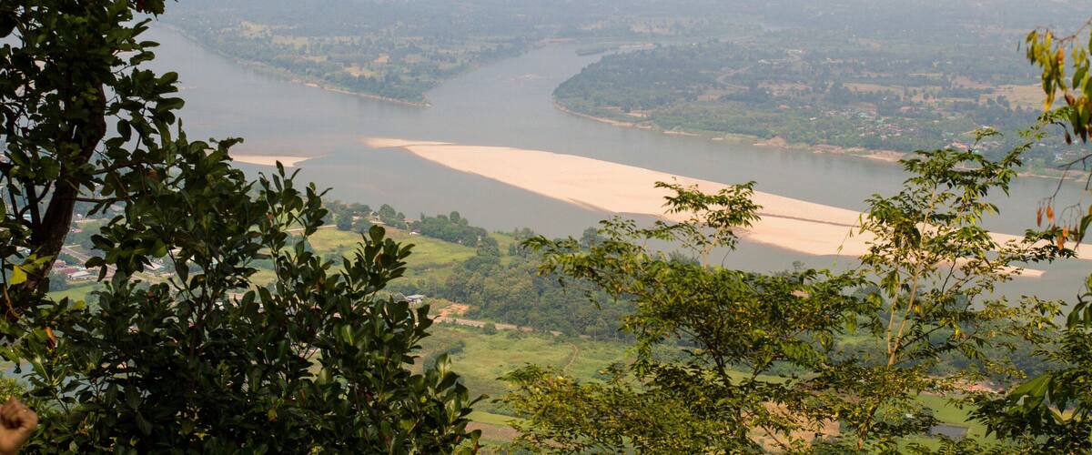 A river winding through a valley with surrounding greenery and distant buildings.