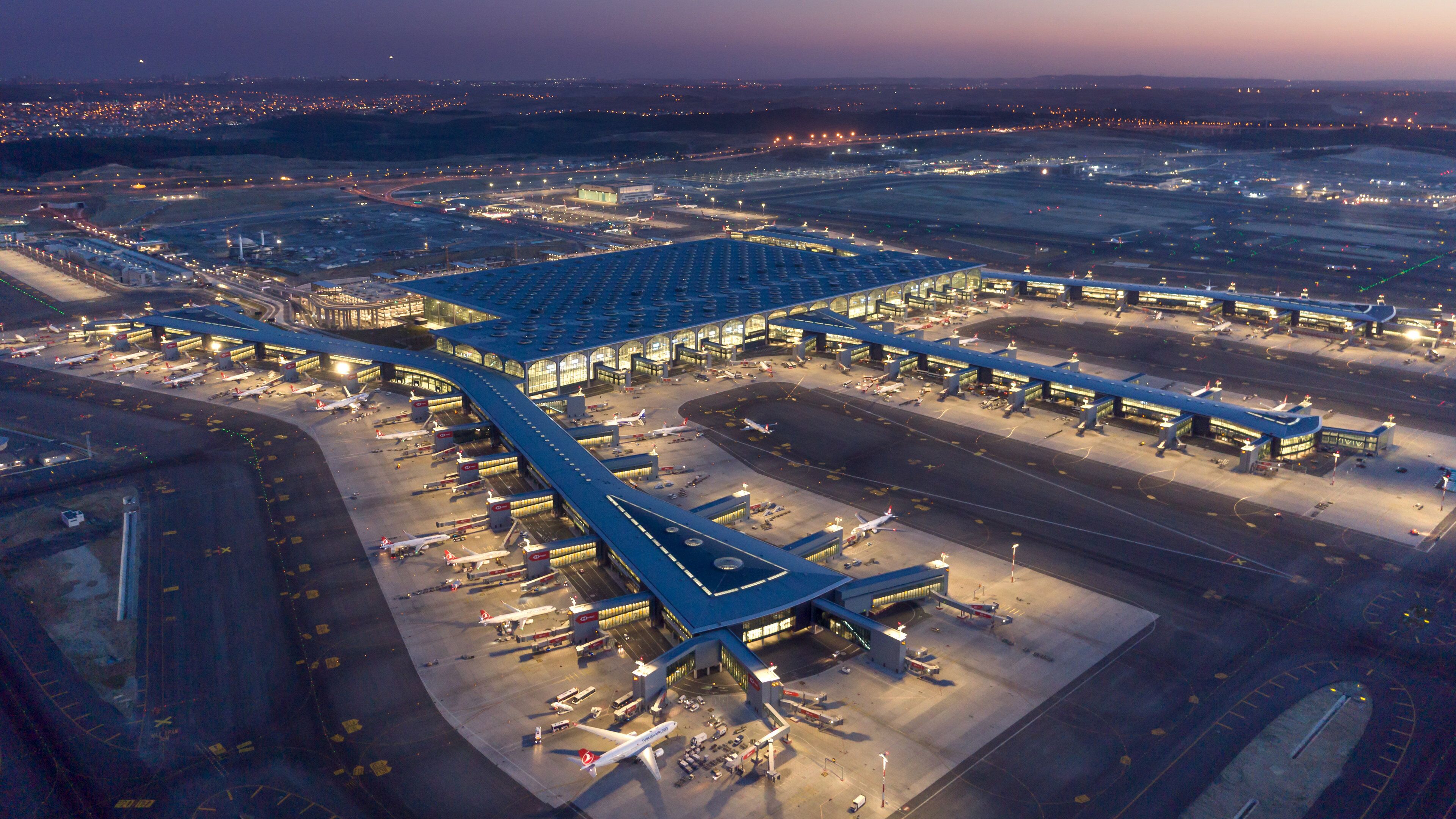 An airport with multiple terminals, runways, and parked airplanes.