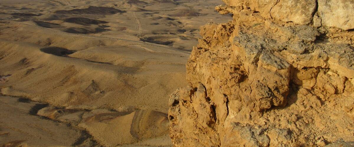 A vast desert landscape with prominent rocky formations and distant hills.