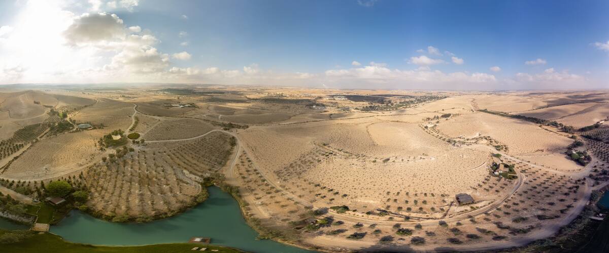 A vast desert landscape with winding roads, terraced fields, and a river.