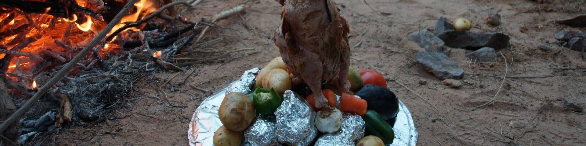 Dinner. An inverted 44 Gallon drum with a spike in the lid. All the vegetables at the bottom cook in the juices of the chicken. Since this is basically a massive dutch oven, the chicken is also super tender. Put the drum on top, seal it up then sit it in coals and put coals on top. Delicious!