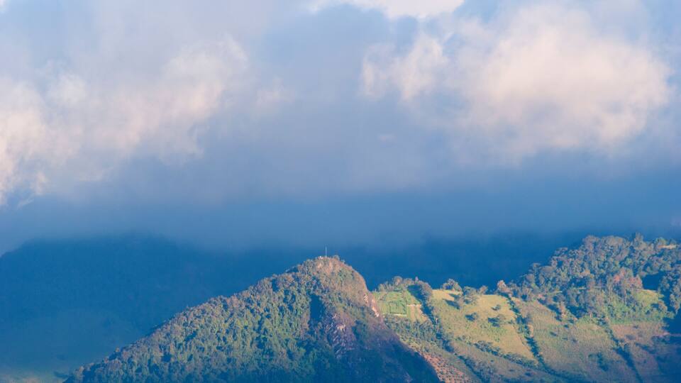 A mountainous landscape with a prominent peak and terraced fields.