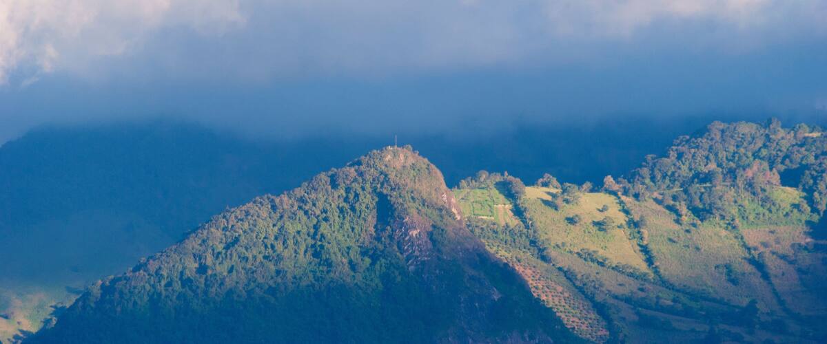 A mountainous landscape with a prominent peak and terraced fields.