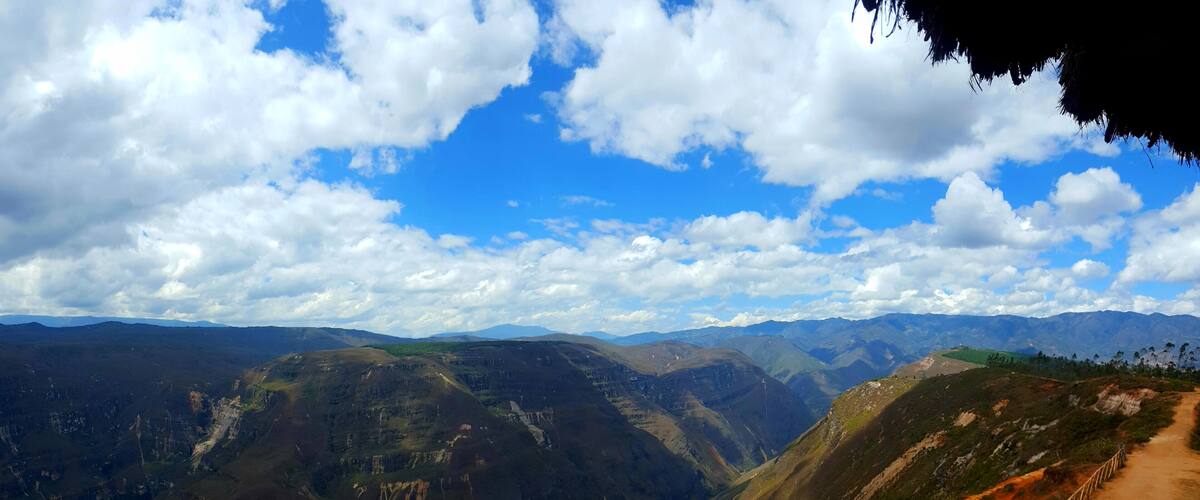 A mountainous landscape with a dirt path and wooden railing.