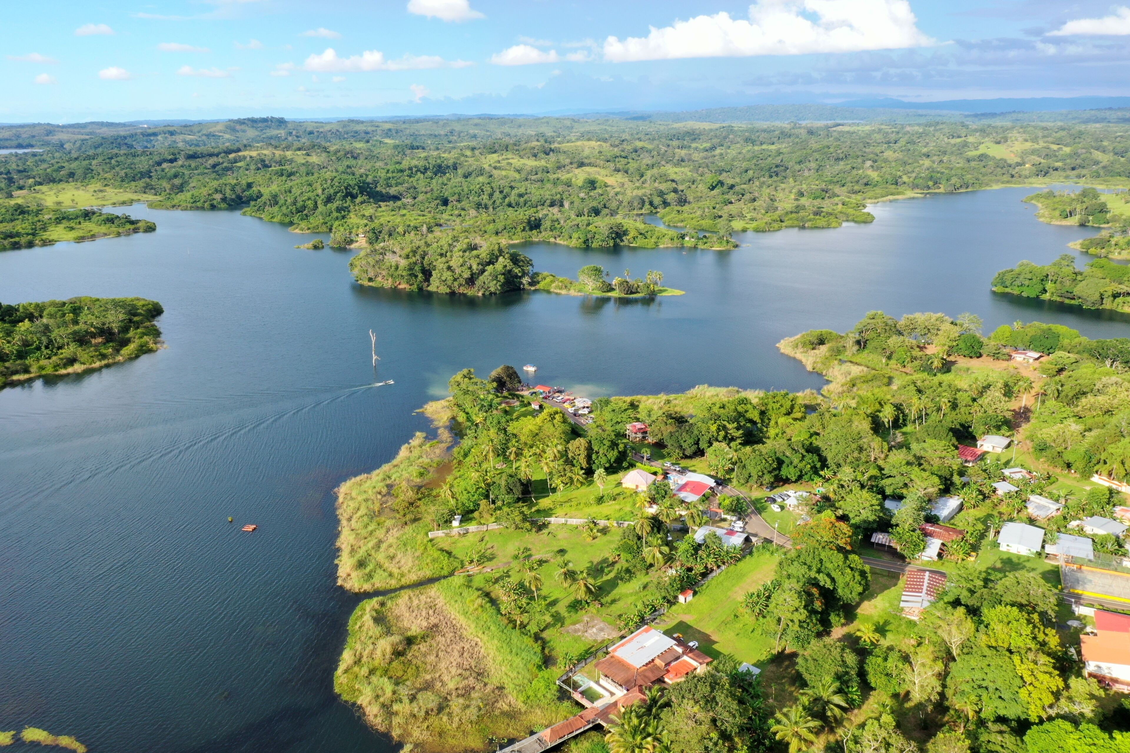 A river winding through a lush landscape with small islands and a cluster of houses near the water's edge.