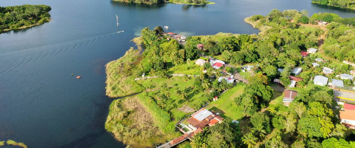 A river winding through a lush landscape with small islands and a cluster of houses near the water's edge.