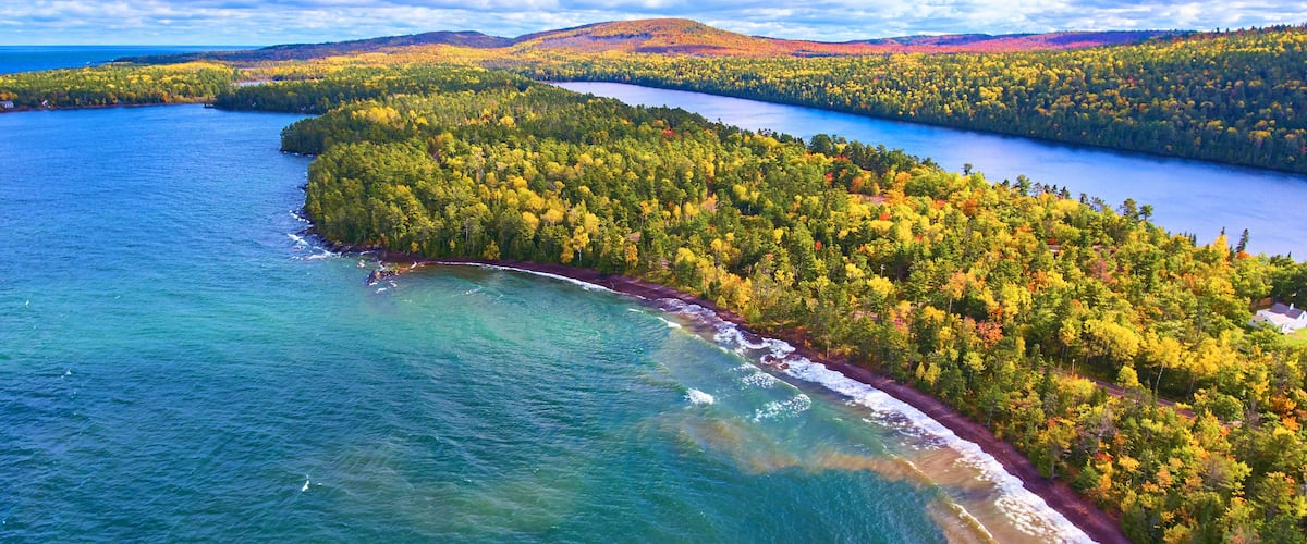 A coastal forested area with a lake and a winding road along the shoreline.