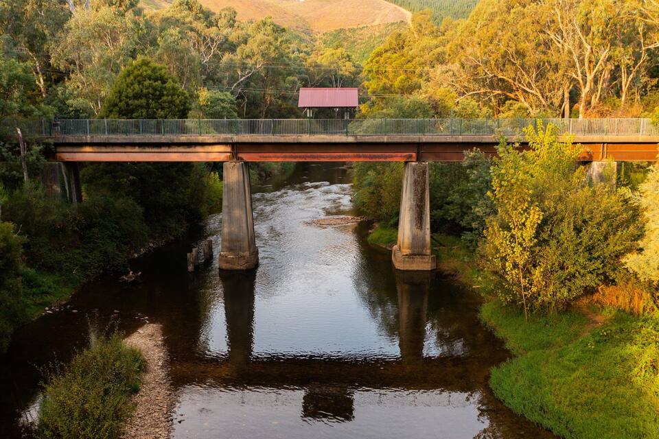 A bridge over a river surrounded by dense greenery and hills.