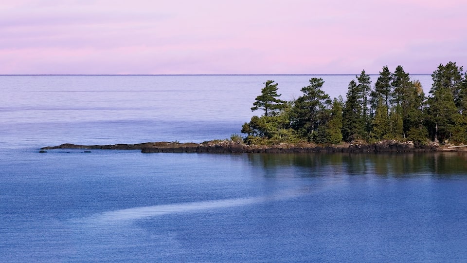 A calm lake with a rocky outcrop and a forested island.