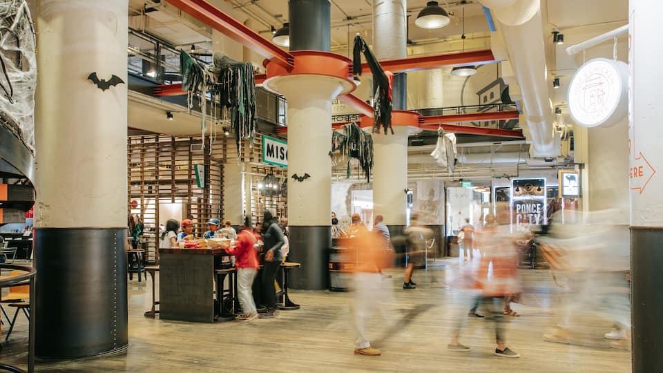 A bustling indoor market with various stalls and people shopping.