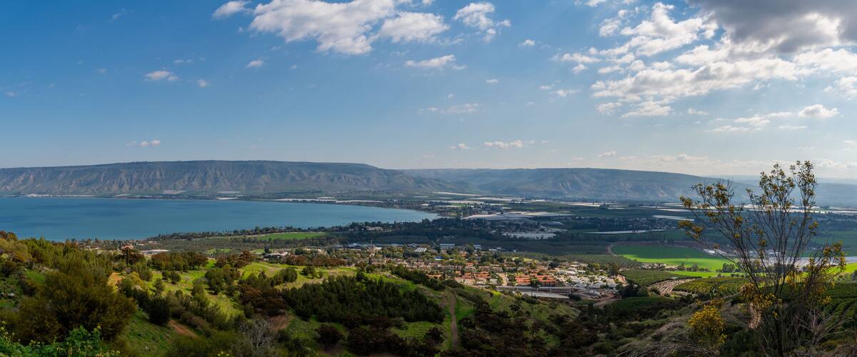 A coastal landscape with a mountain range, a town, and a large body of water.