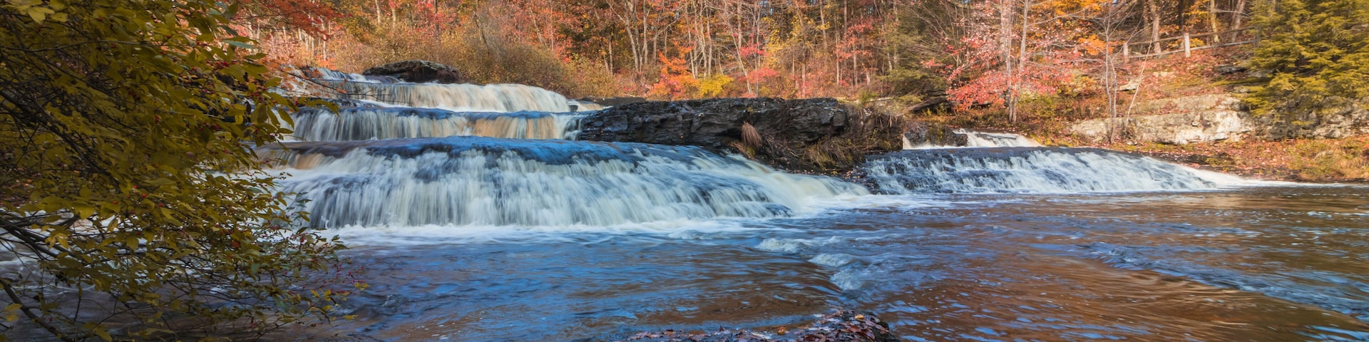 Una cascada en un bosque con follaje otoñal.
