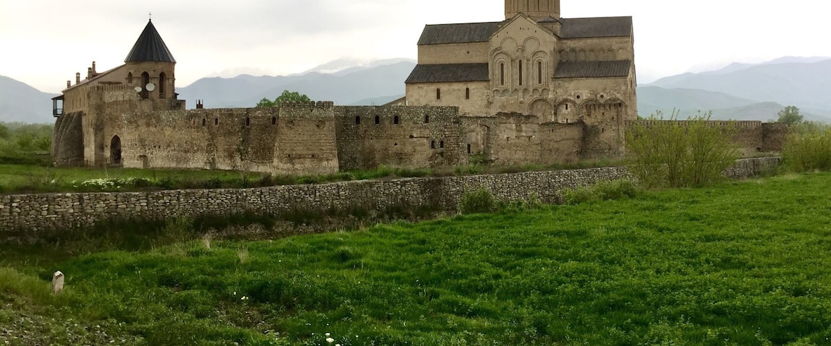 A historic stone fortress with a prominent tower and a smaller building with a conical roof.