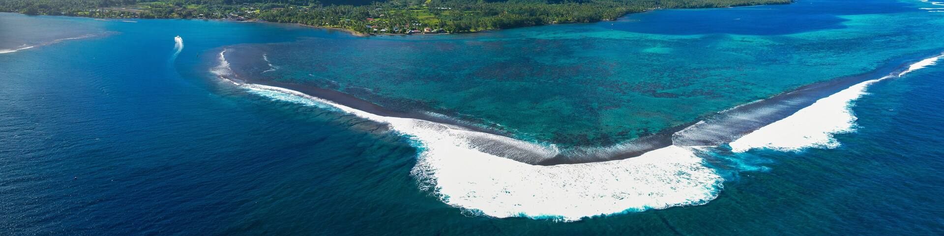 A tropical island with a clear blue sea, white sandy beaches, and lush green mountains.