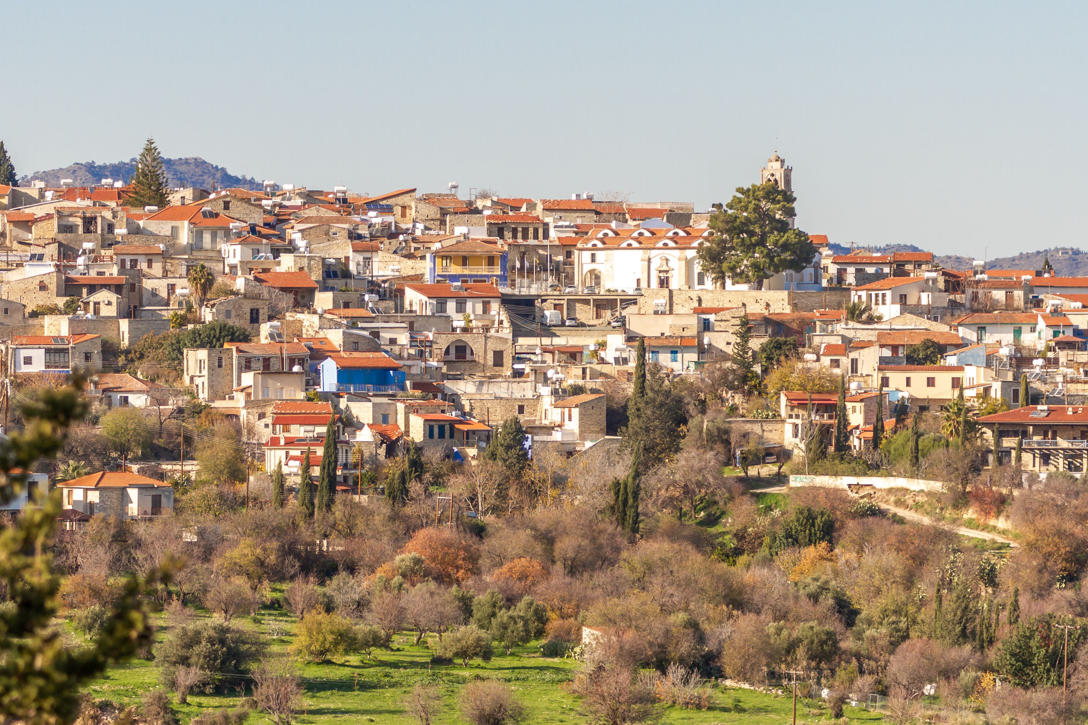 Un pueblo en una ladera con construcciones históricas y una torre de iglesia destacada.