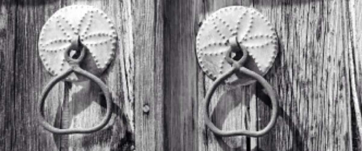 Two metal door knockers on a wooden door.