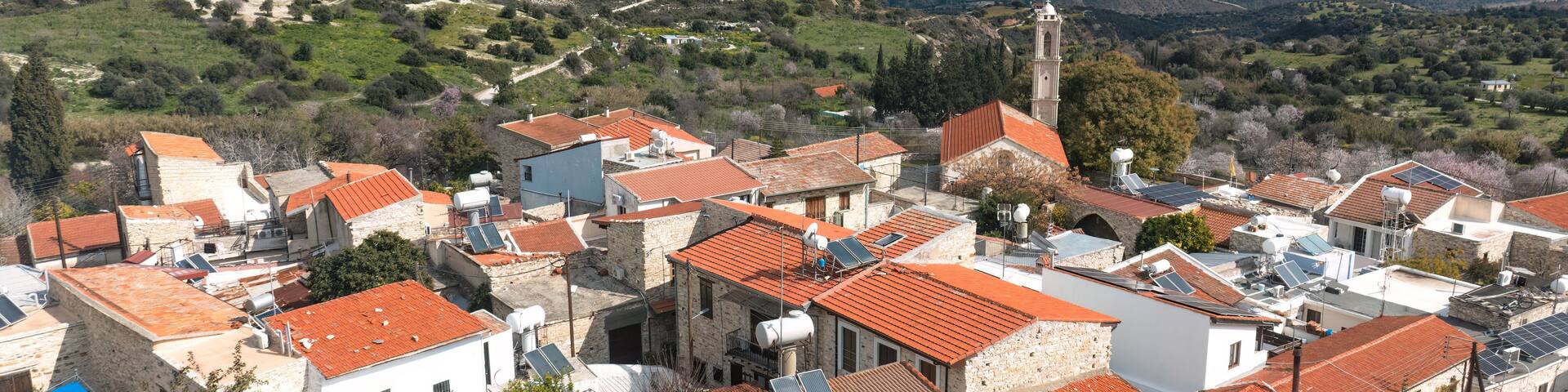 A coastal village with red-tiled roofs, stone buildings, and a prominent church tower.