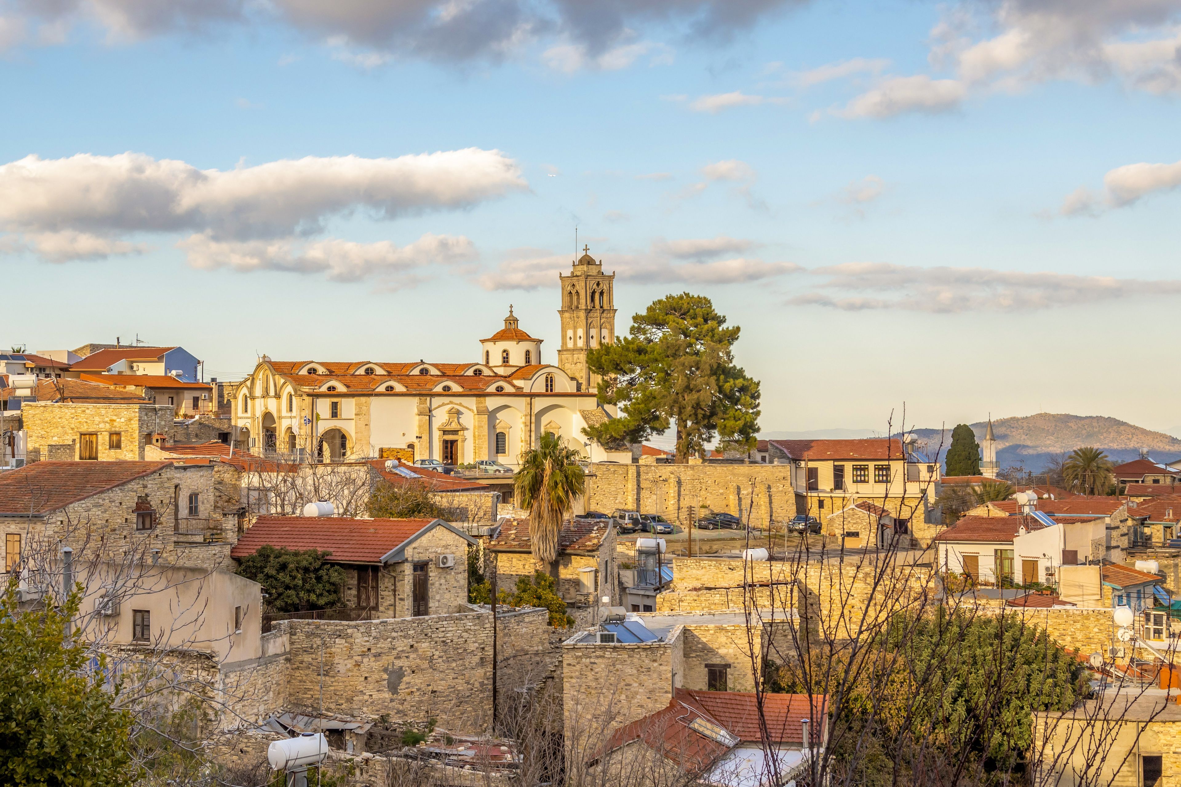 Un pueblo histórico con edificios de piedra, una iglesia destacada con campanario y un cielo despejado.