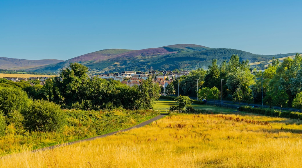 A rural landscape with a village, rolling hills, and a clear sky.