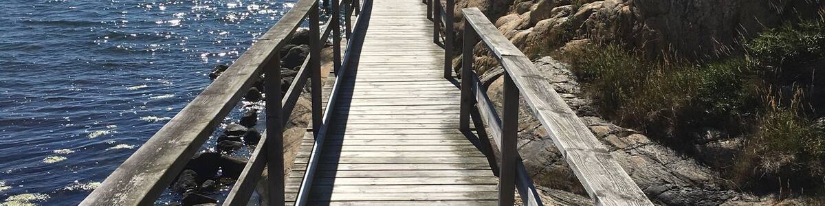 A wooden pier extending into calm waters, surrounded by rocky terrain.