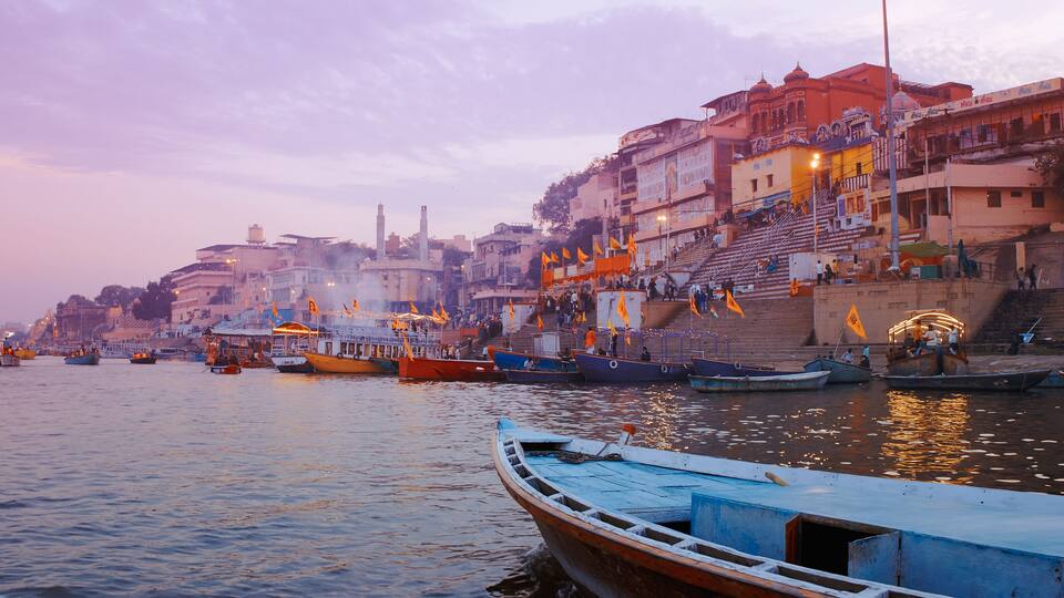Varanasi, Uttar Pradesh, India. Many Boats moored on Ganga river near ghats. Hundreds of tourists and locals come in boats to watch Ganga Maha Aarti ceremony and the fire ceremony. Purple sunset sky