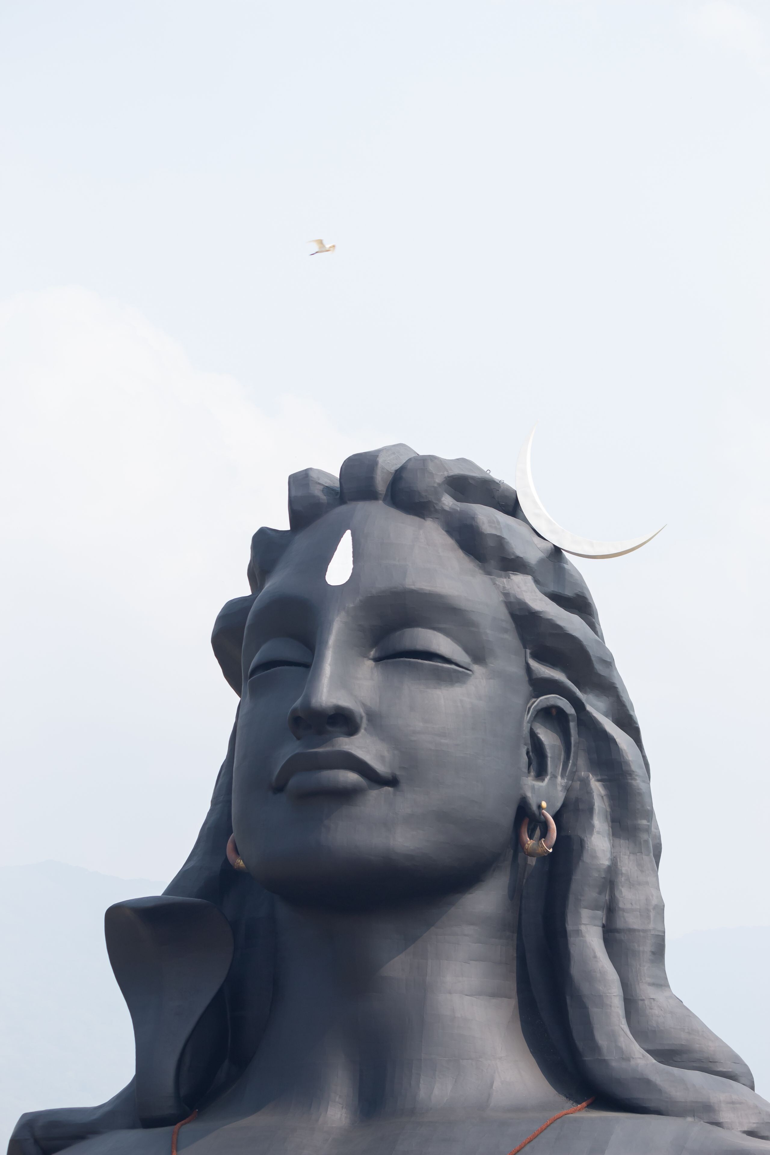 Una estatua imponente con una expresión serena, frente a un cielo despejado.