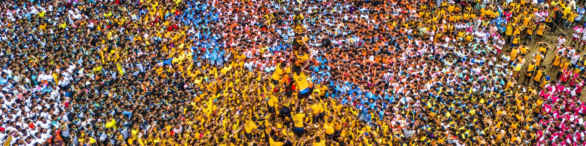 Aerial view of vibrant dahi handi festival with colorful crowd celebrating in traditional attire, Thane, India.