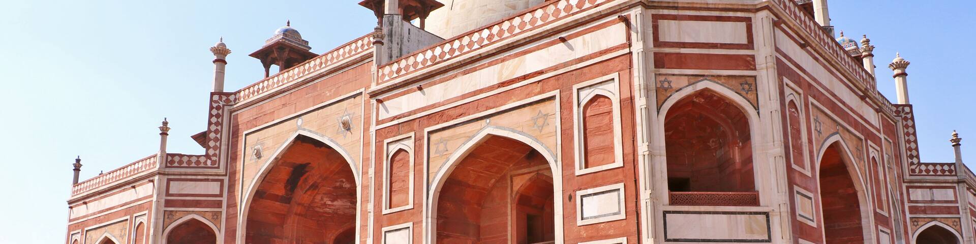 A large, ornate building with domes and arches, featuring intricate patterns and a spacious courtyard.