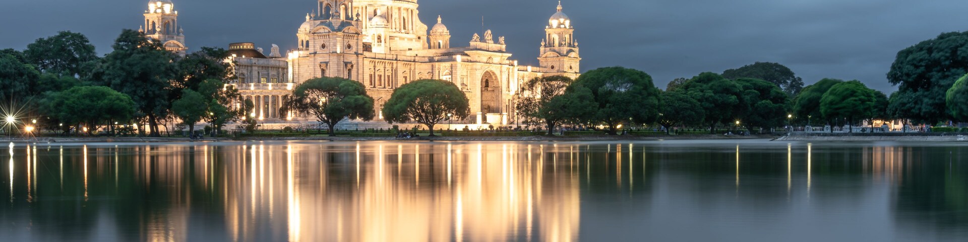 A grand, illuminated cathedral with a large dome, reflecting on a calm lake.