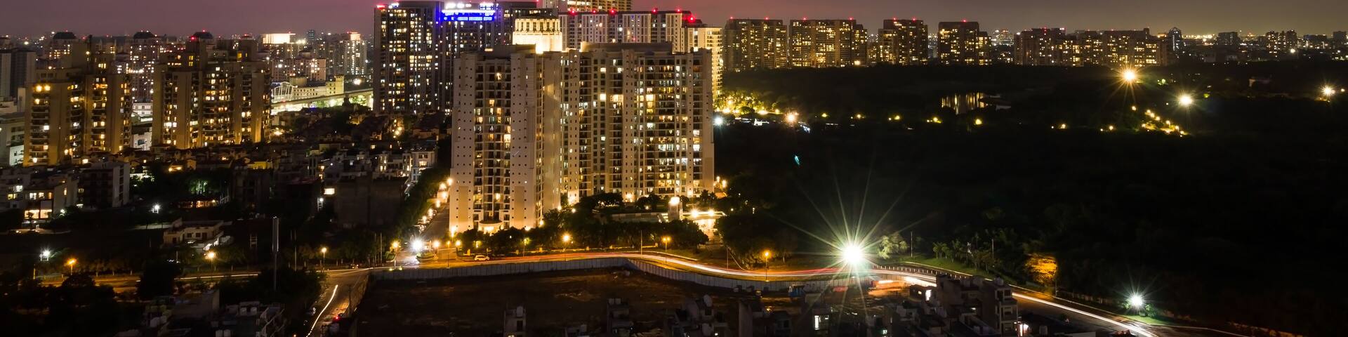 Beautiful view of city lights,light trails,colorful sky at night during monsoons in Delhi NCR’s posh locality with urban cityscape,residential apartments and commercial business hub on July 20,2021.