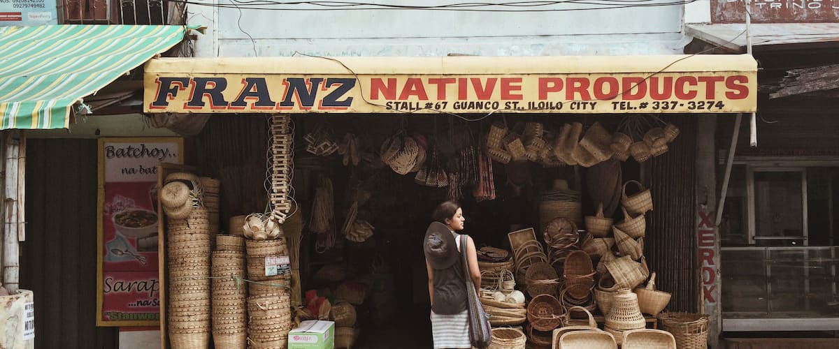 A storefront with a sign reading "FRANZ NATIVE PRODUCTS" and a variety of woven baskets and containers displayed outside.