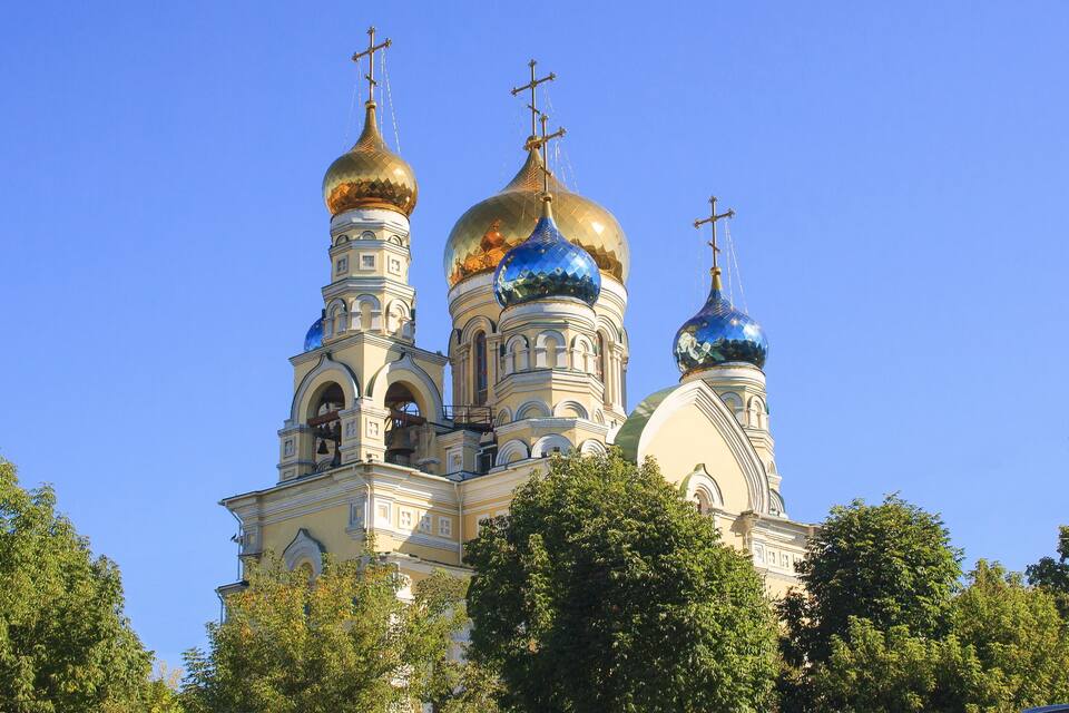 Una iglesia con tres cúpulas doradas y fachada blanca.