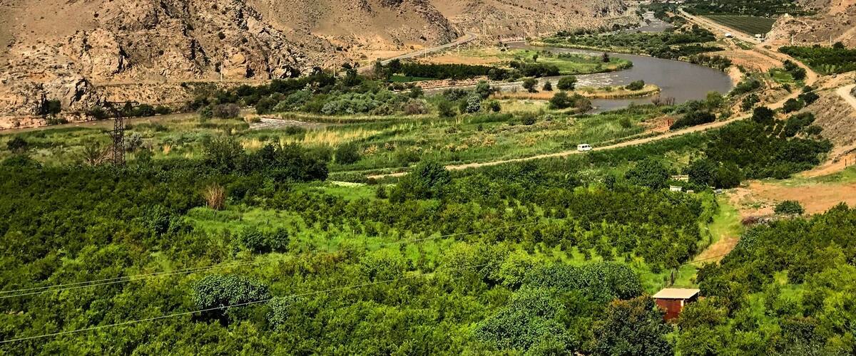 A mountainous landscape with a river and green fields.