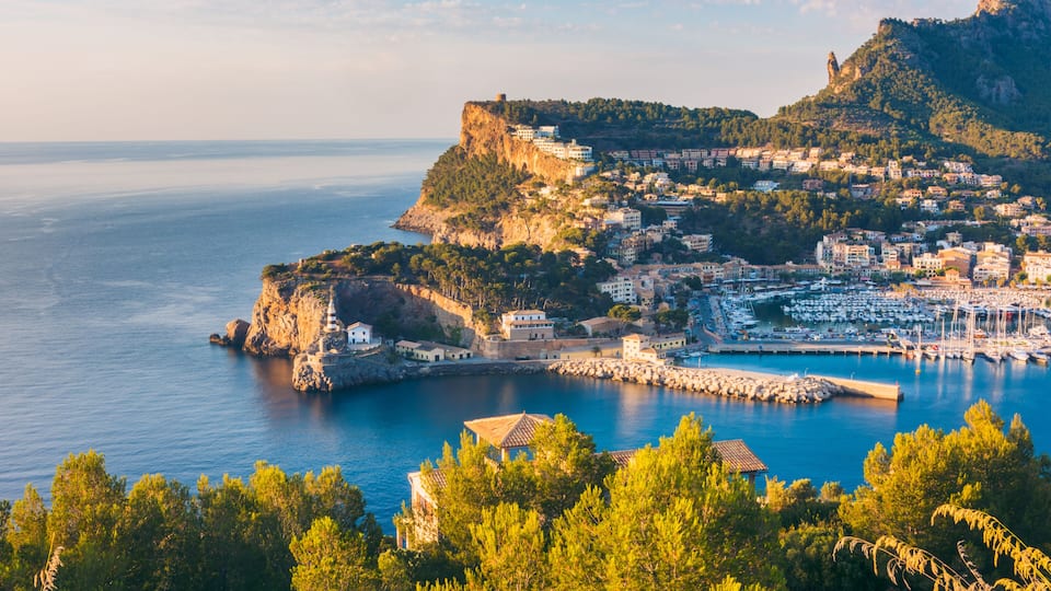 A coastal town with a prominent cliff, a marina, and lush greenery.