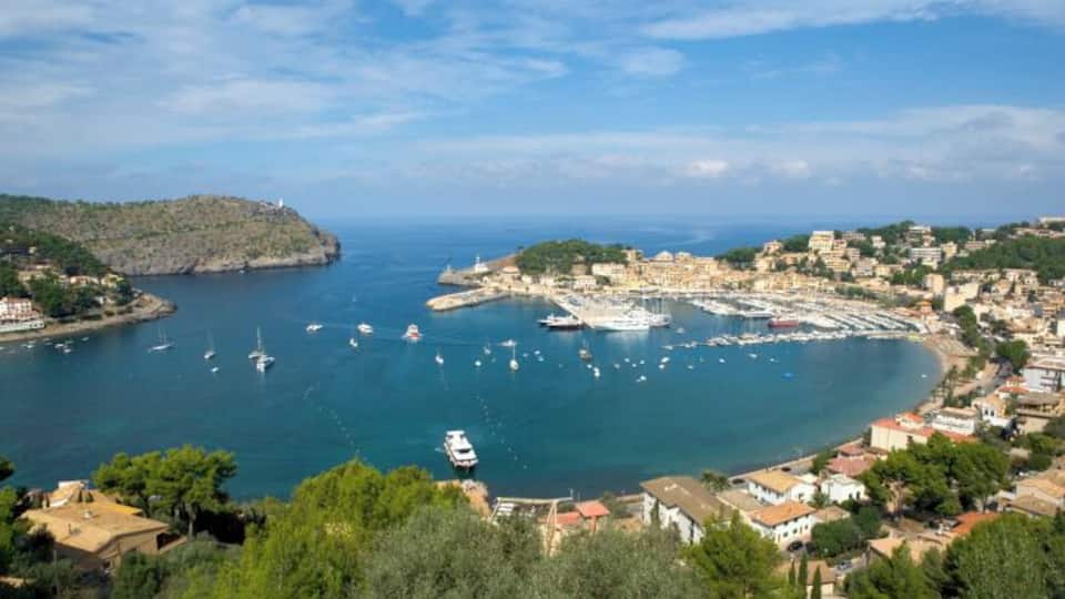 A coastal town with a marina, boats, and buildings along the waterfront.