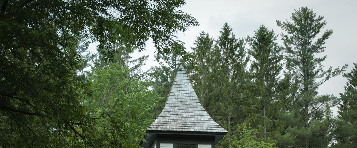 A white church with a bell tower, surrounded by trees.