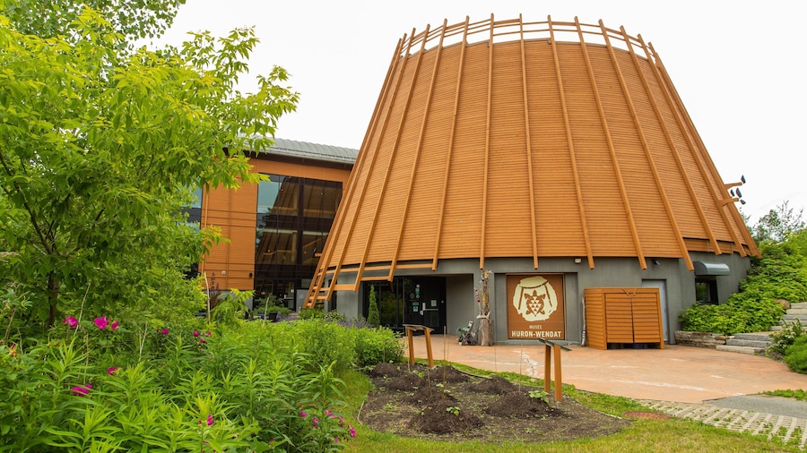 Un museo con un techo de madera cónico distintivo y un letrero que dice "MUSEE HURON-WENDAT".