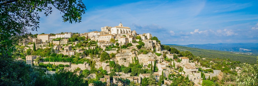 A historic town built on a hillside with ancient stone buildings and lush greenery.