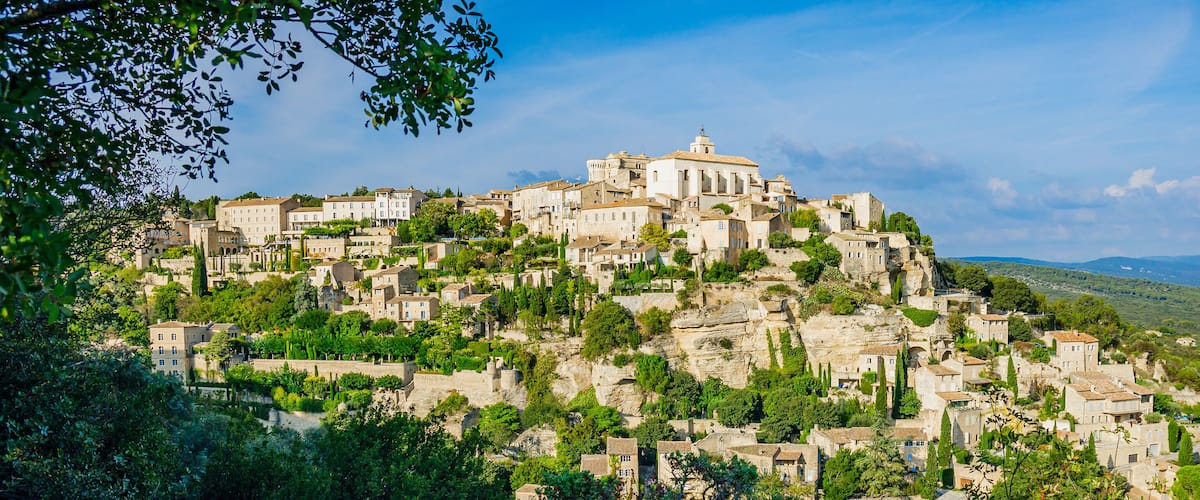 A historic town built on a hillside with ancient stone buildings and lush greenery.