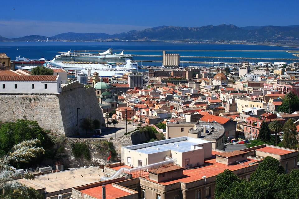 Une ville côtière dotée d’une architecture historique, où un grand navire de croisière est amarré, et qui abrite une imposante forteresse en pierre.