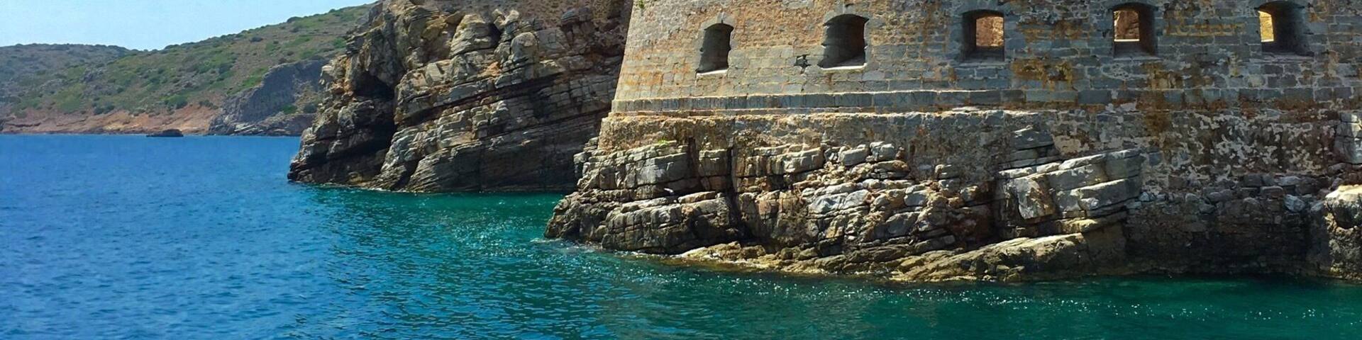 Une fortification côtière bordée d’eaux d’un bleu limpide et de falaises rocheuses.