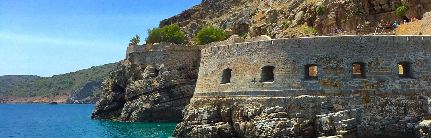 Una fortificación costera con aguas azul turquesa y acantilados rocosos.
